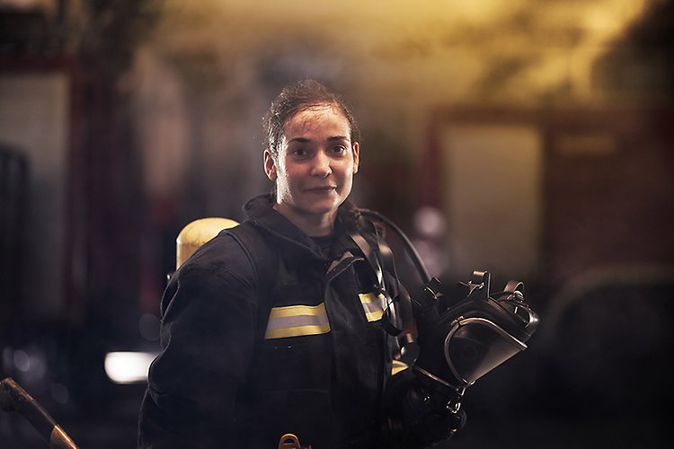 Kvinnlig brandman i rökdykarutrustning utan mask